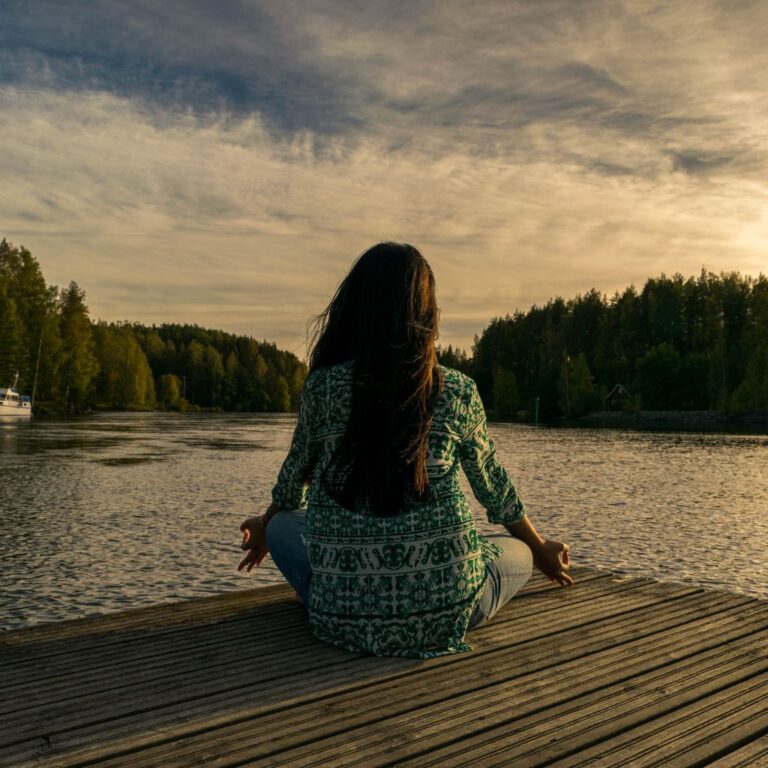Naine mediteerimas järve ääres